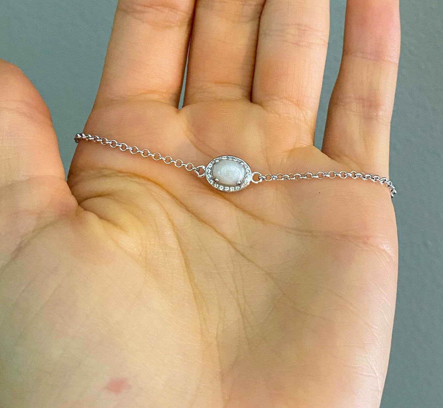Sterling silver cremation bracelet with an oval white gemstone, surrounded by a halo of smaller stones, a beautiful and simple piece of memorial jewelry