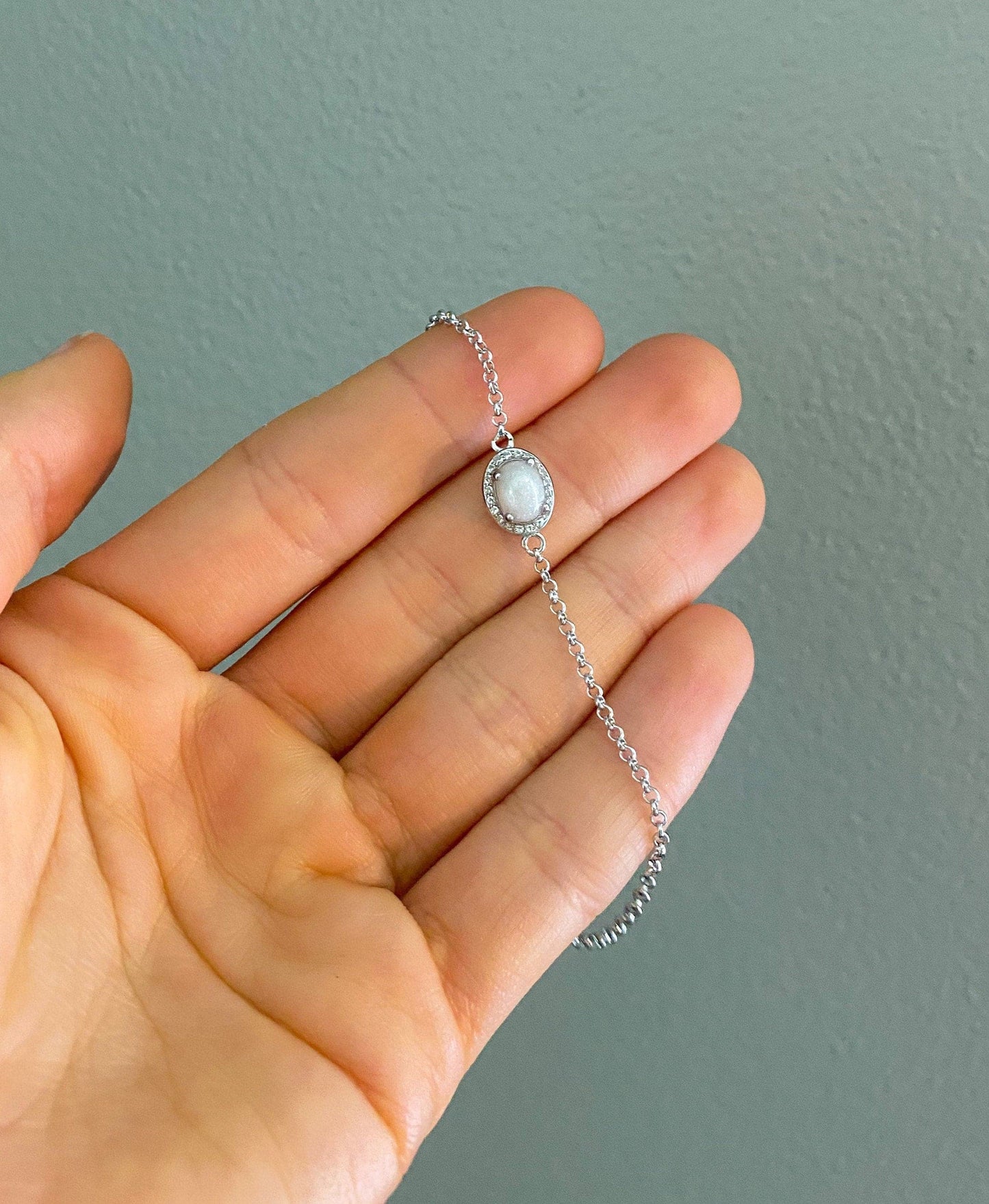 Sterling silver cremation bracelet with an oval white gemstone, surrounded by a halo of smaller stones, a beautiful and simple piece of memorial jewelry