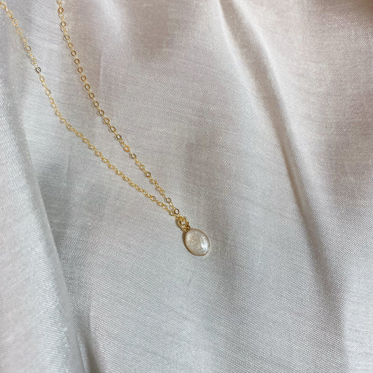 Simple gold chain necklace with a small, oval pendant, designed as a personalized cremation ashes jewelry piece or keepsake.